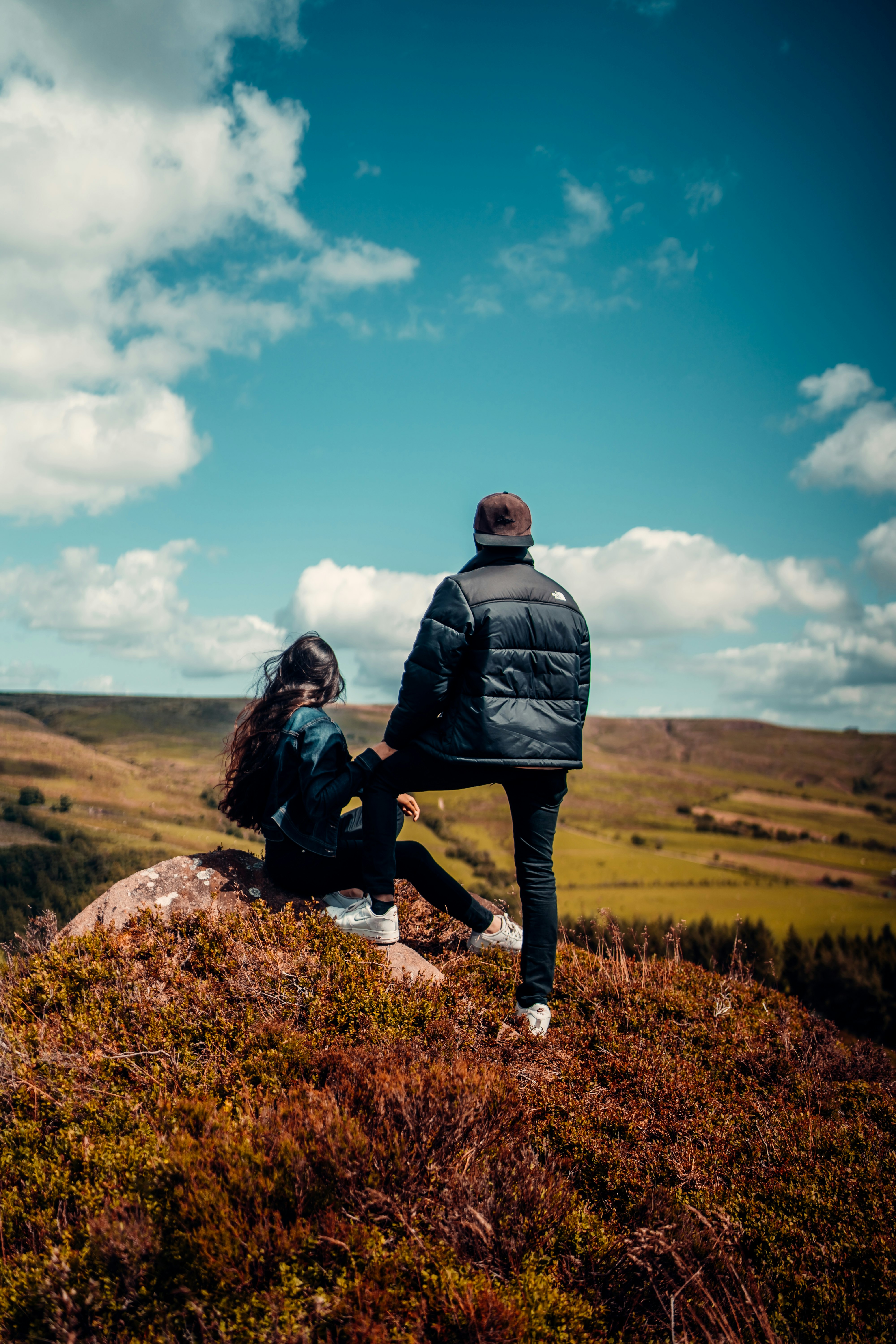 man and woman standing on brown grass field under blue sky during daytime